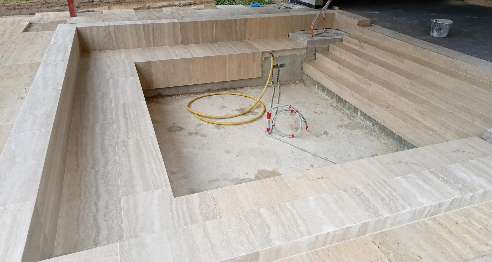 Piscine en cours de réalisation avec margelles, assises et marches en pierre naturelle claire